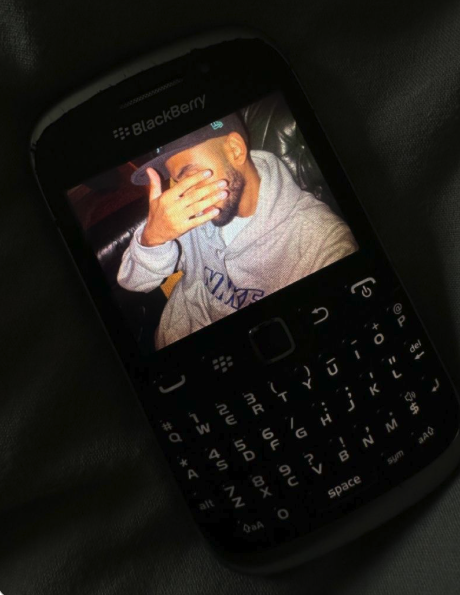 A vintage BlackBerry phone on a desk under dramatic light